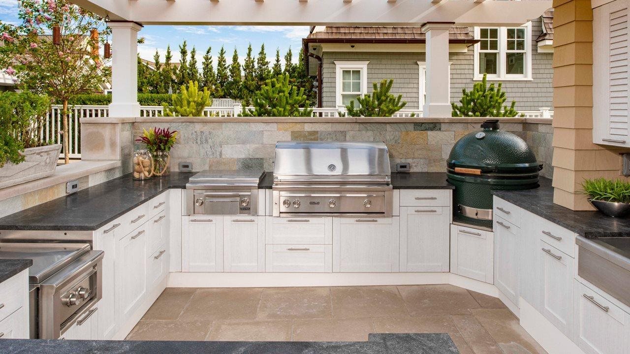 outdoor kitchen with stove oven and grill on tile patio with pergala