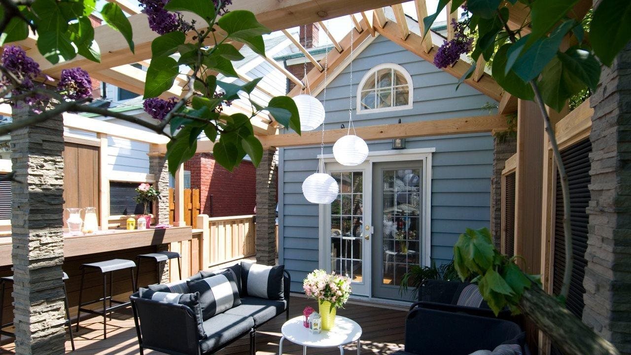 Creative privacy in backyard featuring outdoor livingroom and bar area with vine-covered pergala